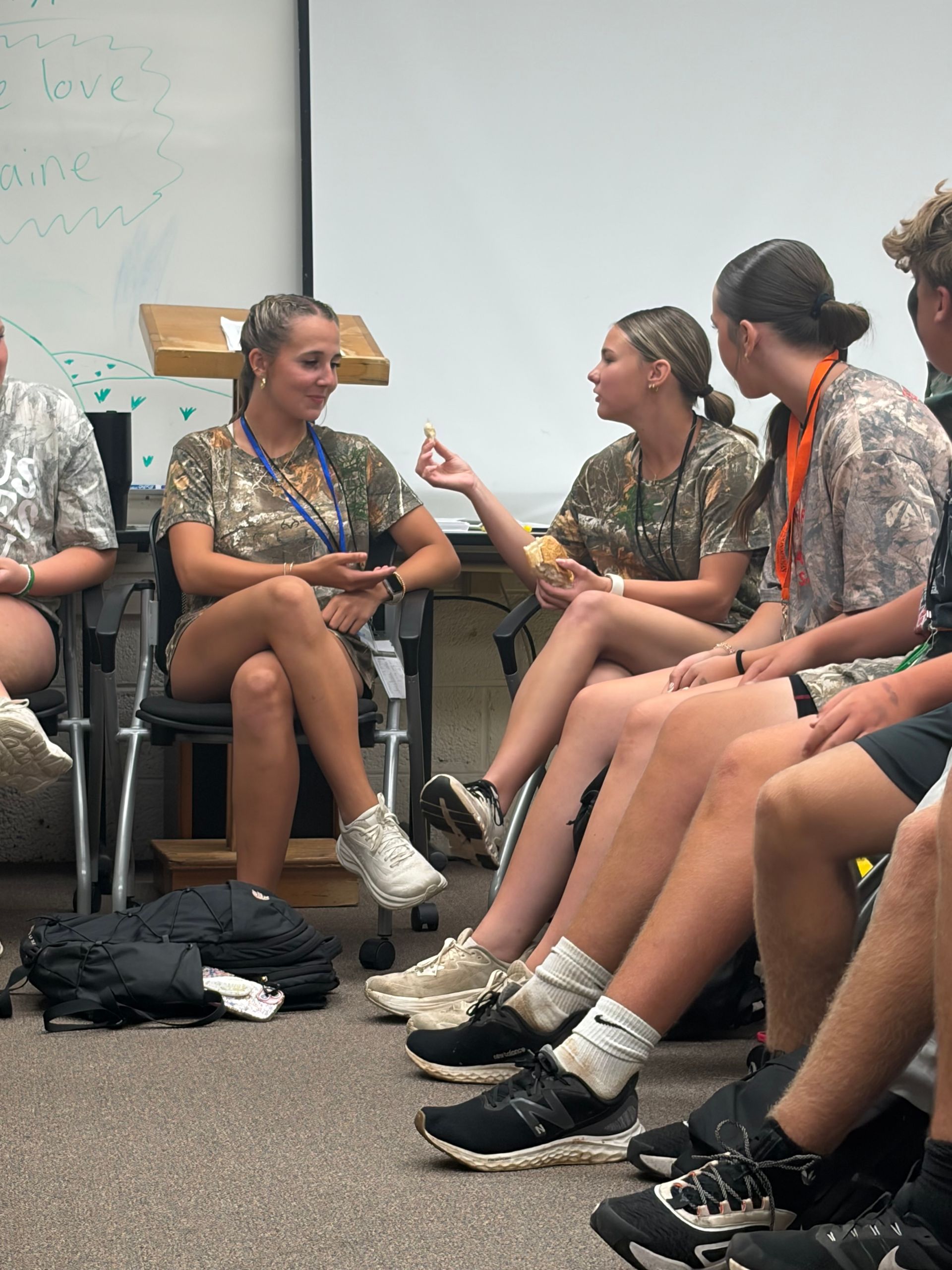 Teenagers seated in a circle during a discussion, with one person gesturing while speaking.