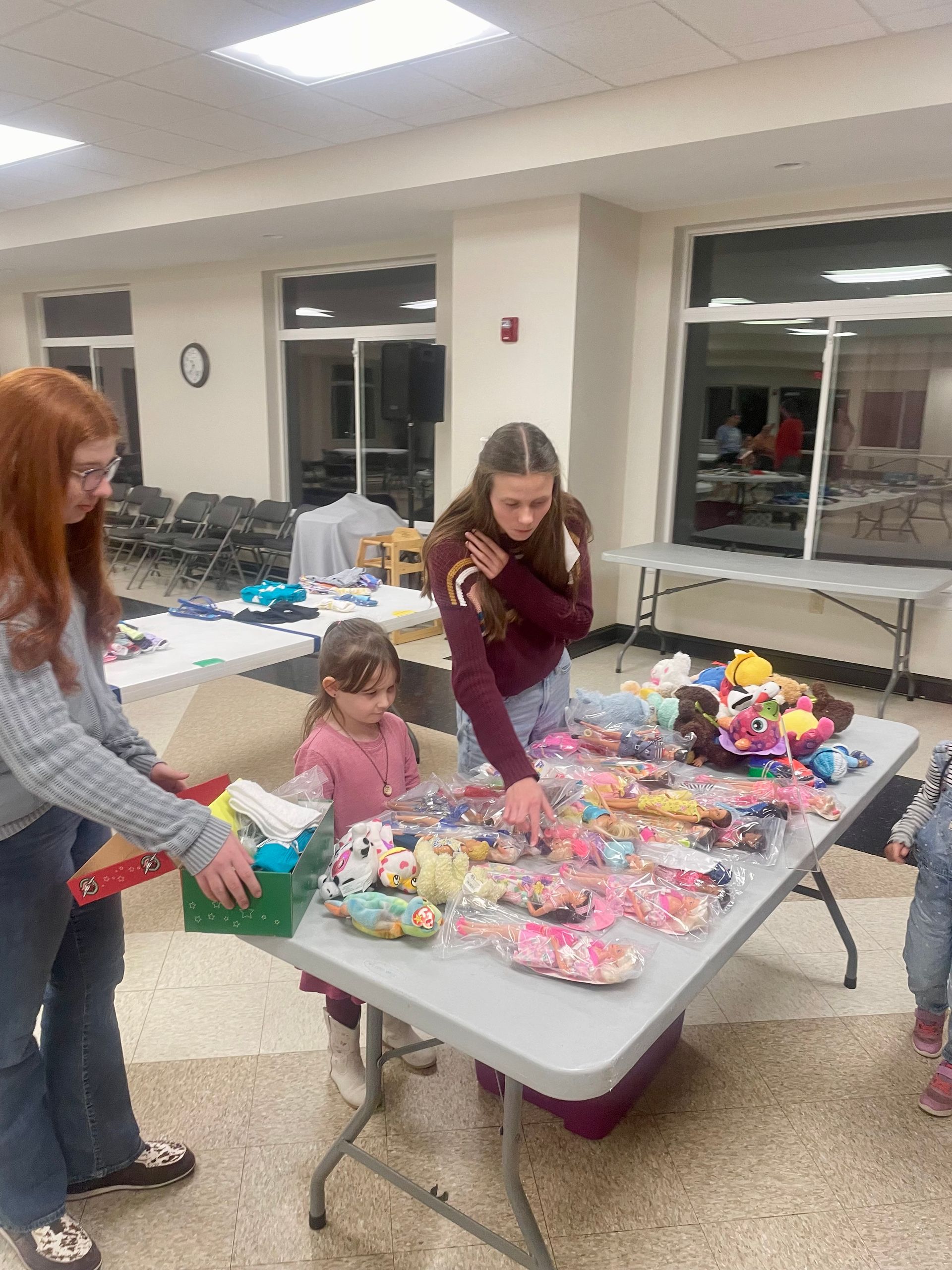 Teenagers arranging colorful crafts on a table in a bright indoor room