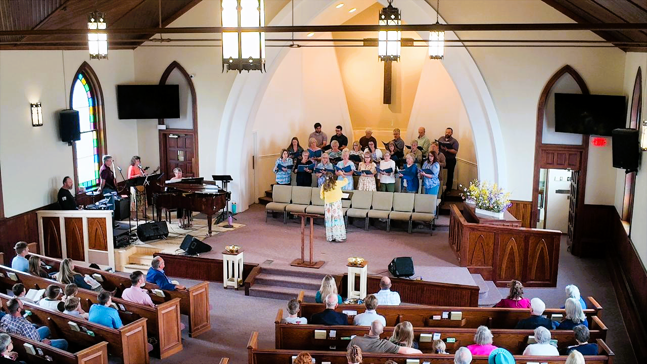 Church service with choir on stage, music minister directing choir.