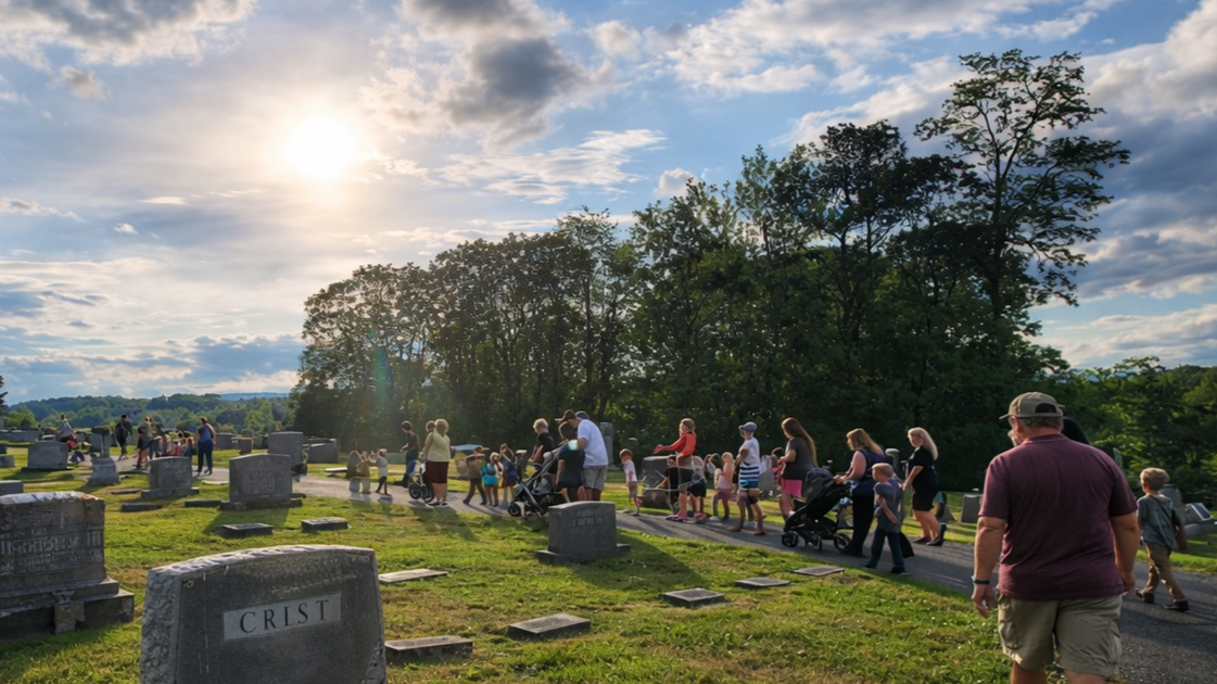 People walking among cemetery graves at sunset under a bright cloudy sky