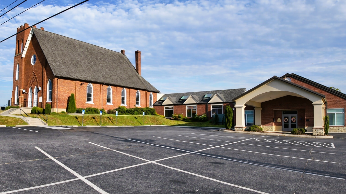 Family entering a brick church through open white doors, with greeter welcoming them at the entrance
