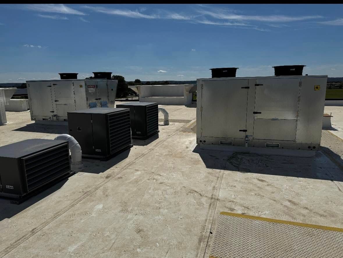Rooftop view with HVAC units. Gray and black machinery on a flat roof under a blue sky.