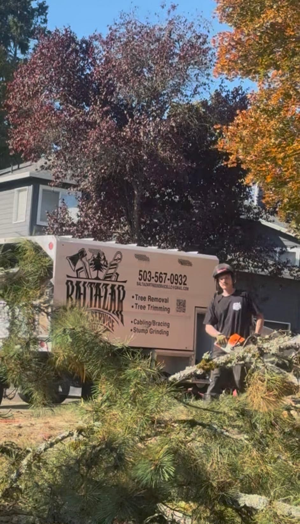 Person sitting by a sign amid autumn trees and a house
