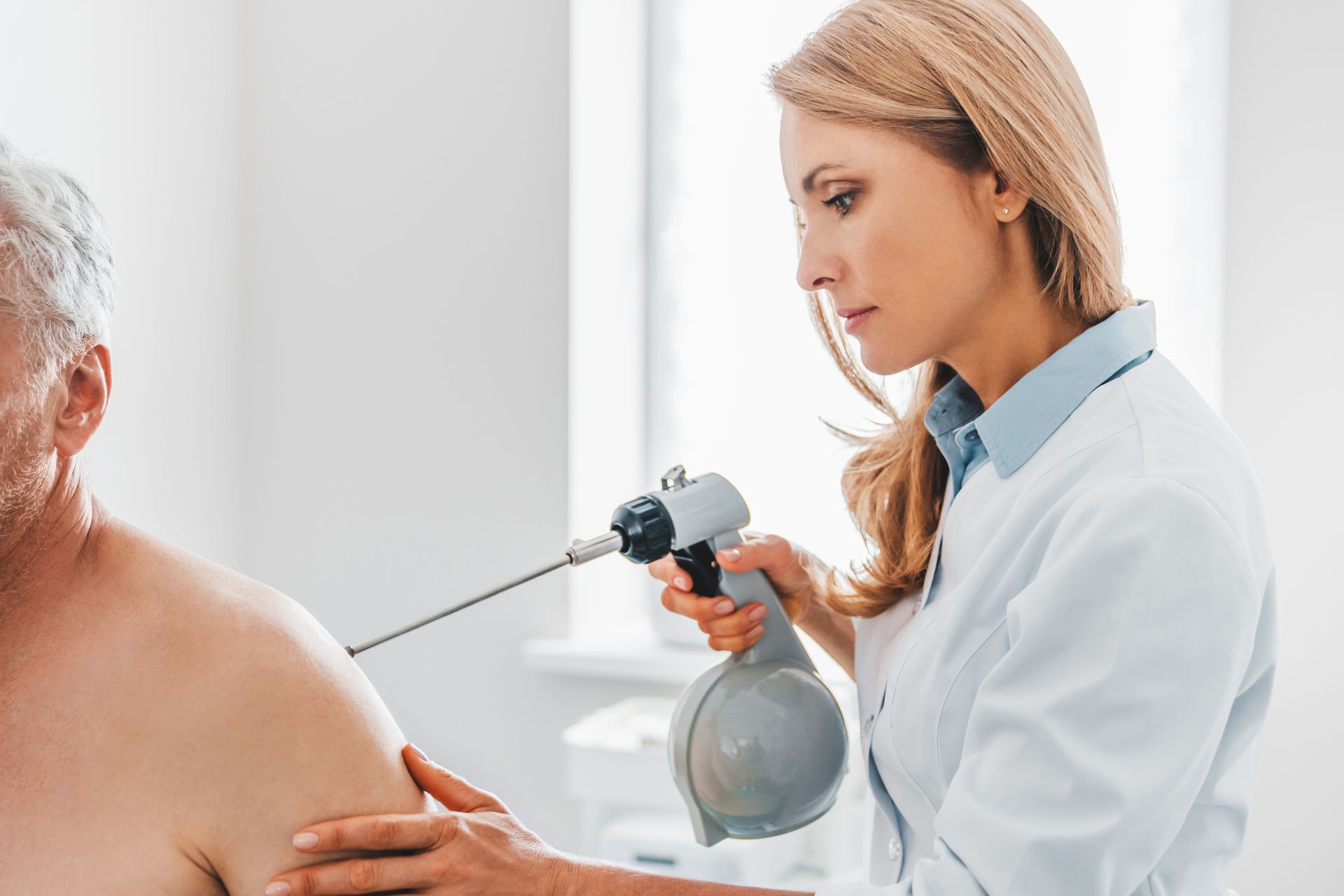 A doctor is examining a patient 's shoulder with a machine.