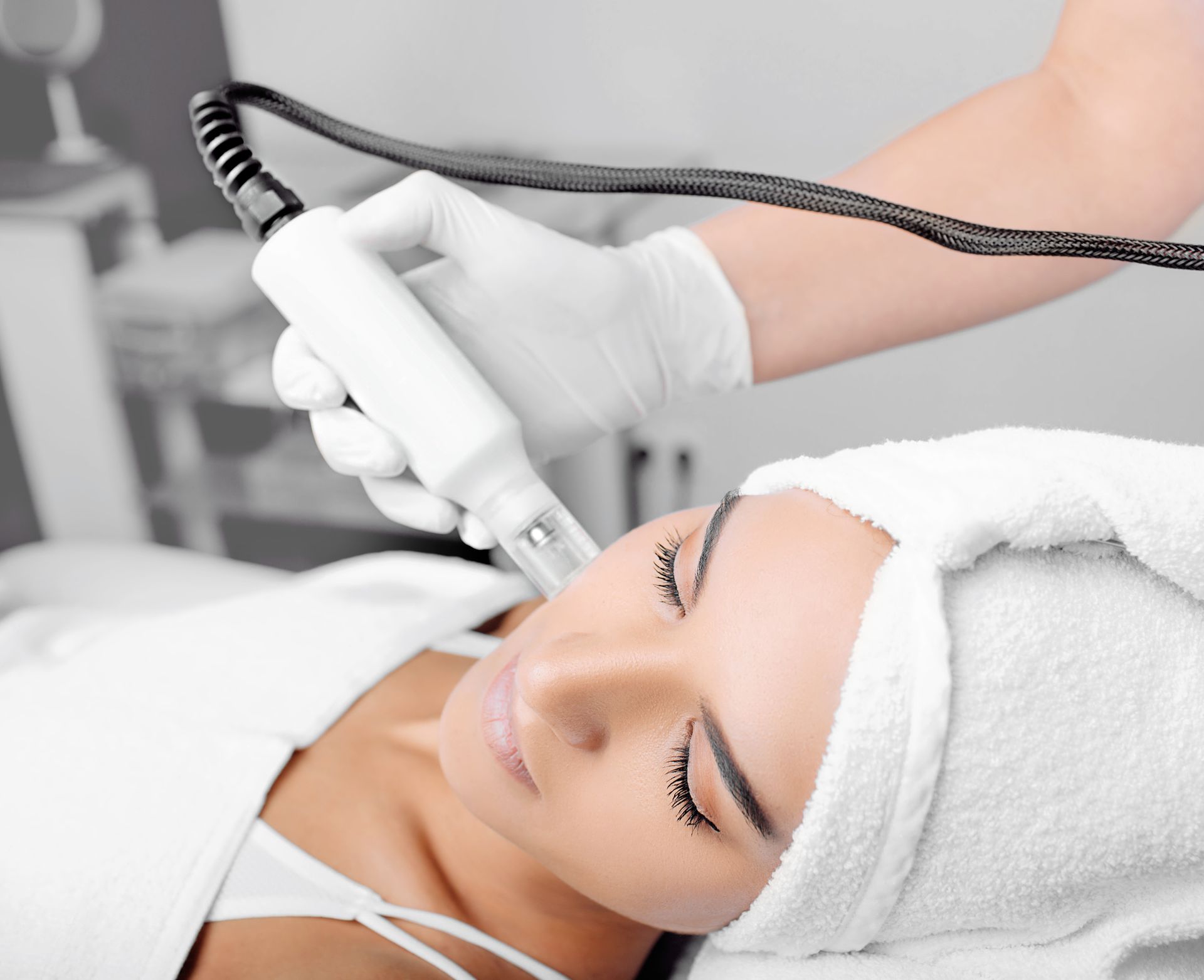 A woman with a towel wrapped around her head is getting a facial treatment
