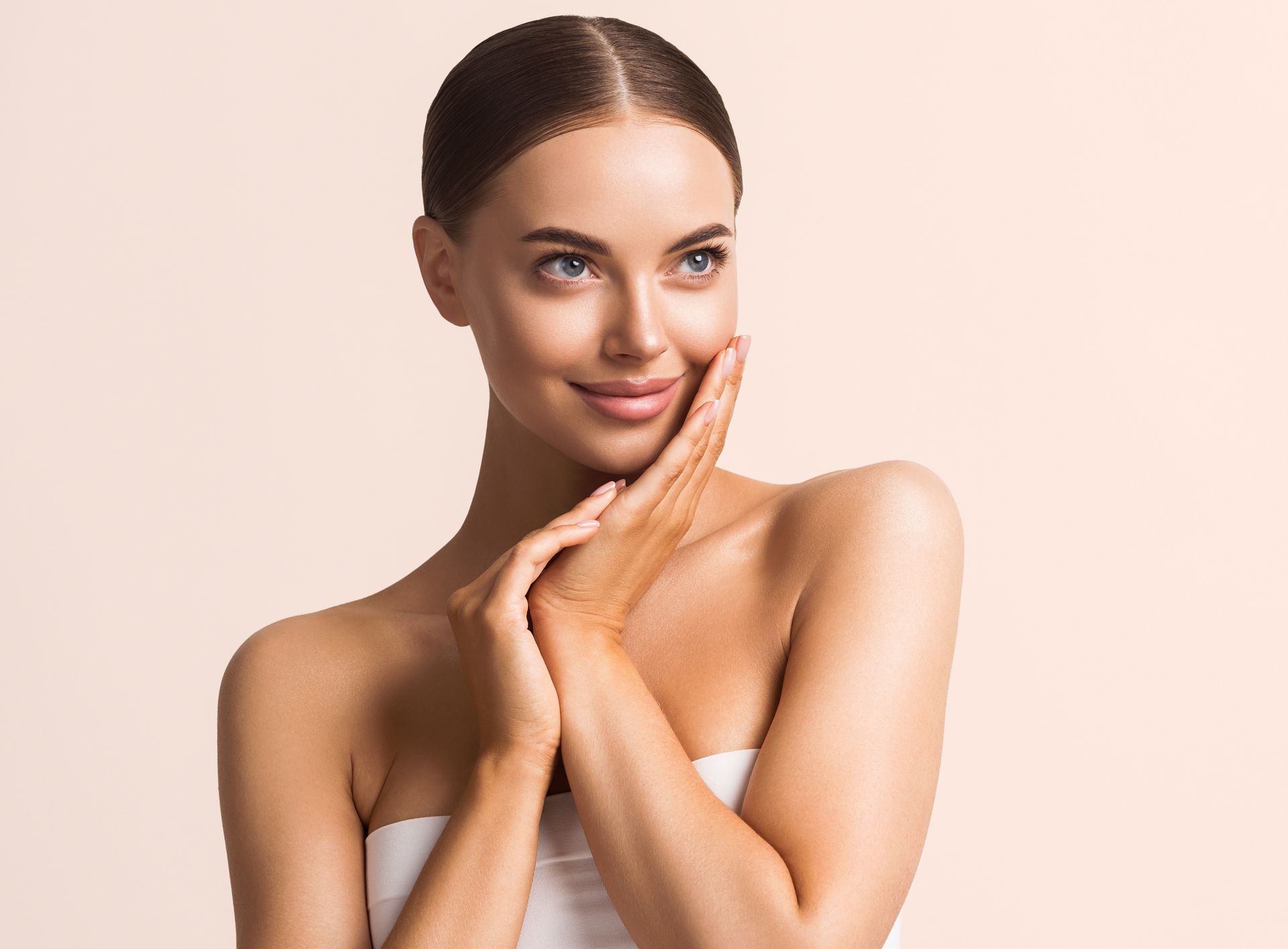 A woman is touching her face with her hands and smiling.