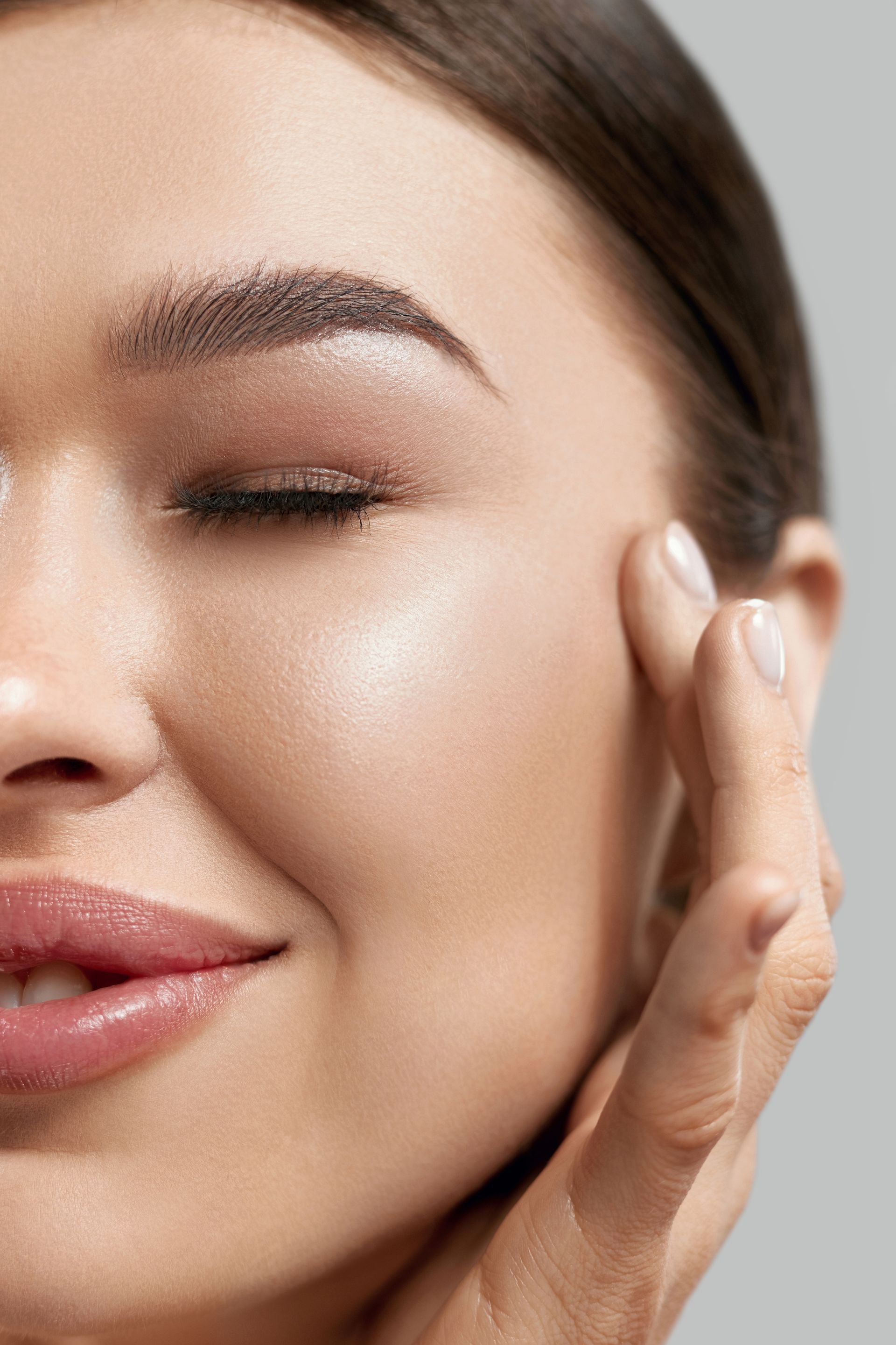 A close up of a woman 's face with her eyes closed and her hand on her face.