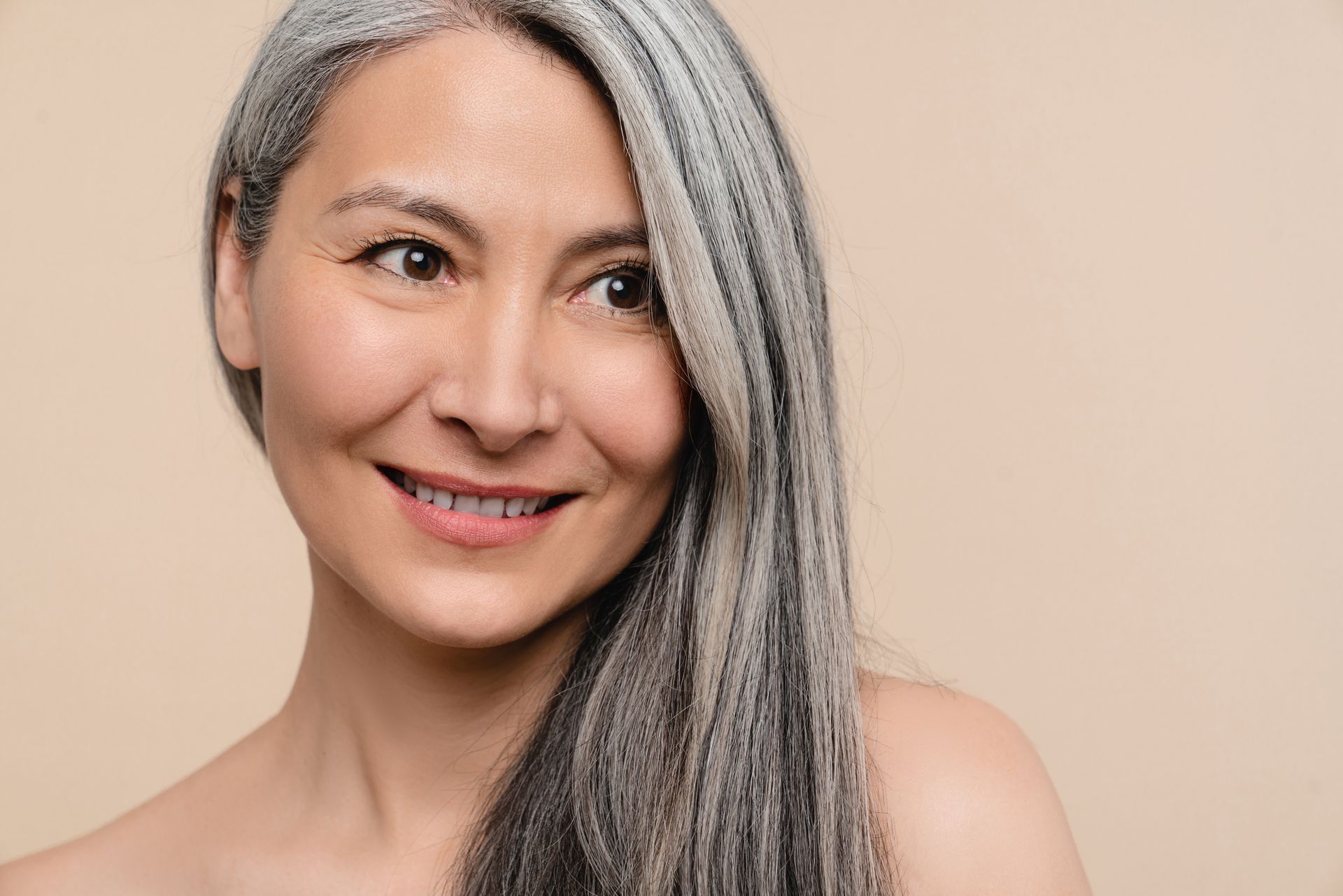 A woman with gray hair is smiling and looking at the camera.