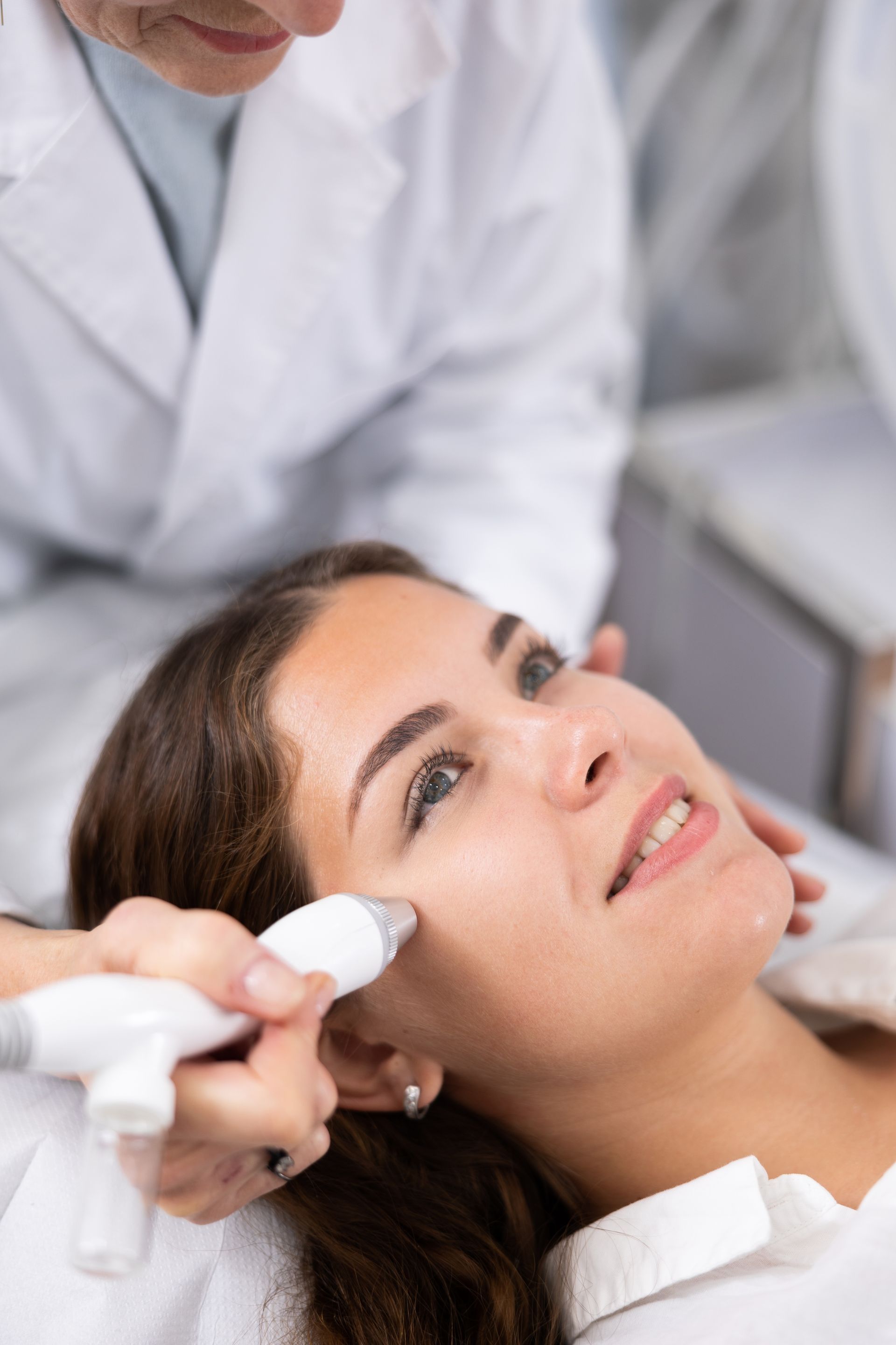 A woman is getting a facial treatment from a doctor.