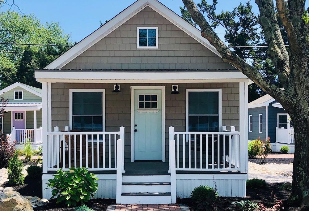 A small house with a white porch and a blue door