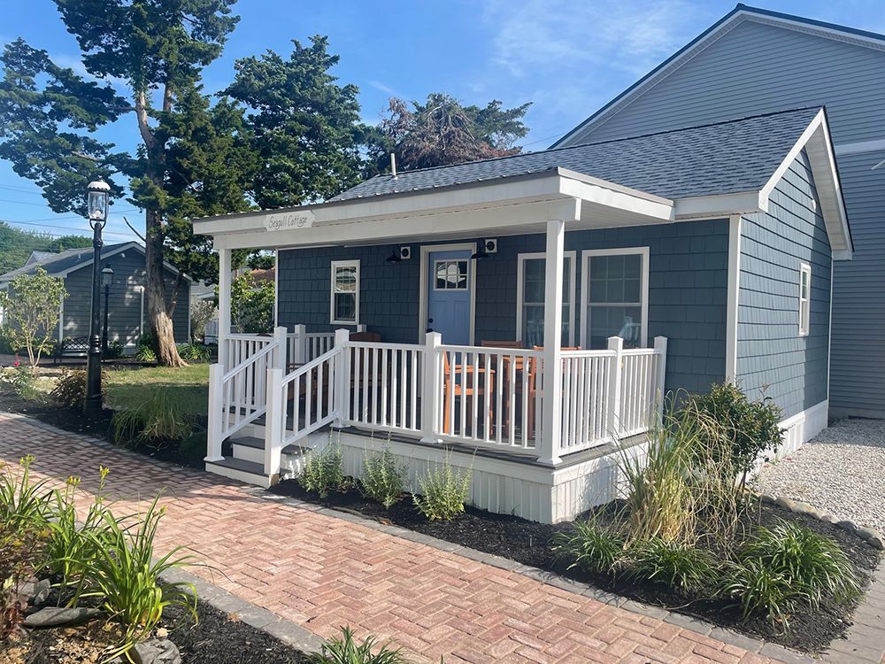 A small blue house with a white porch and stairs.