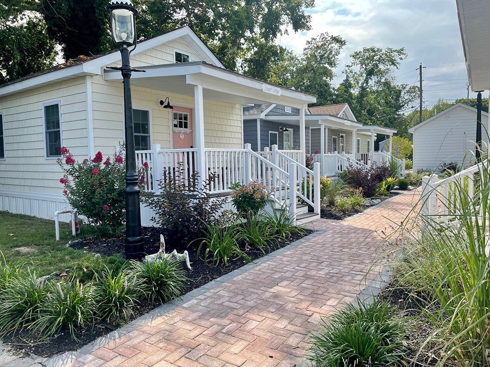 A small house with a porch and a brick walkway leading to it.