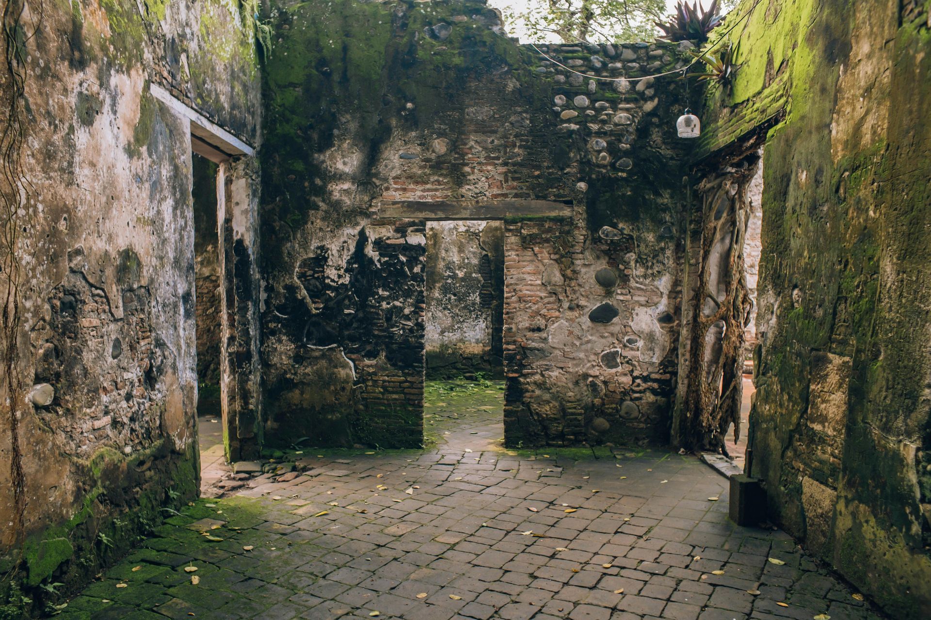 A brick building with moss on the walls and a brick walkway.