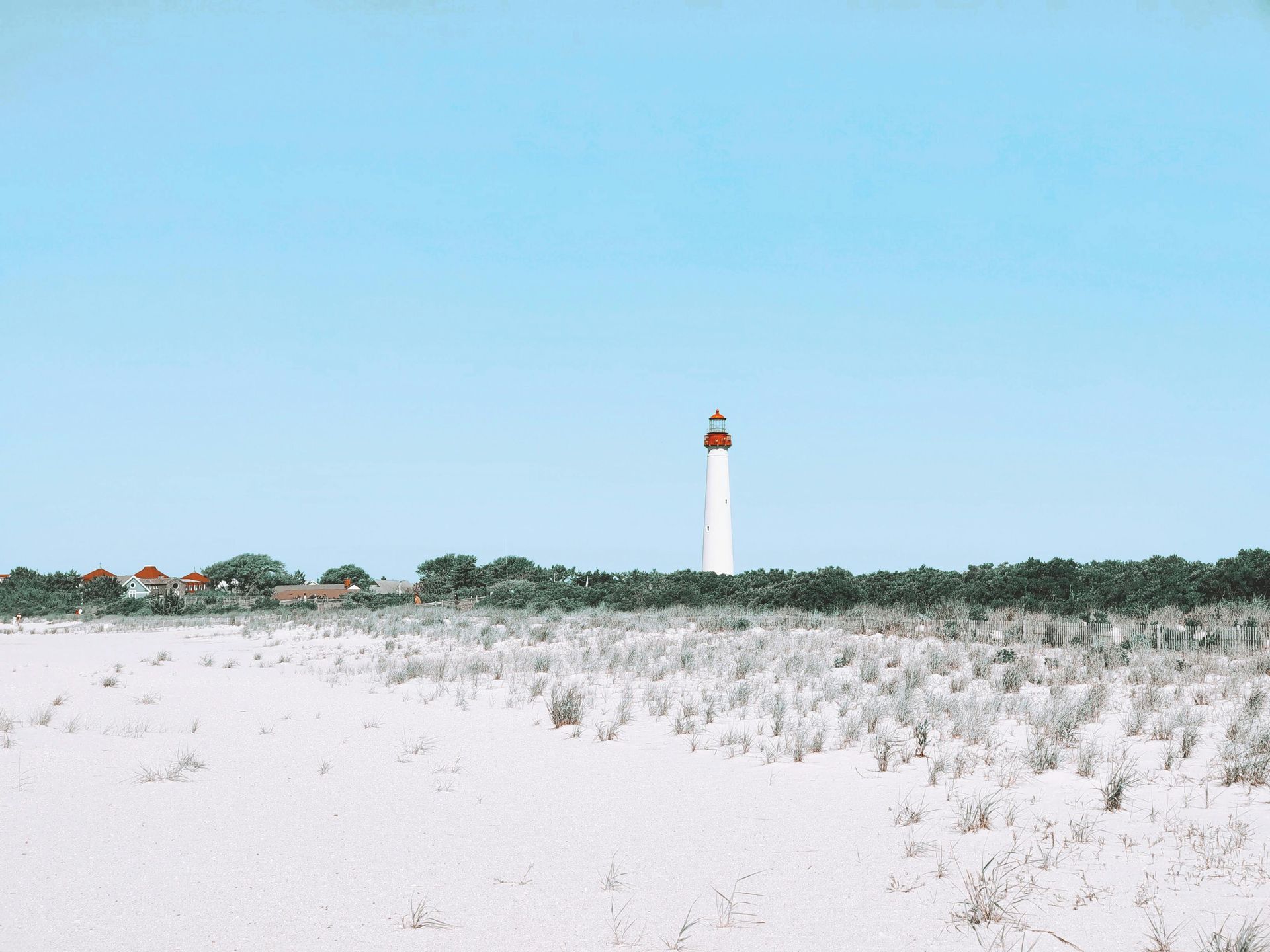 A lighthouse is sitting in the middle of a snowy field.