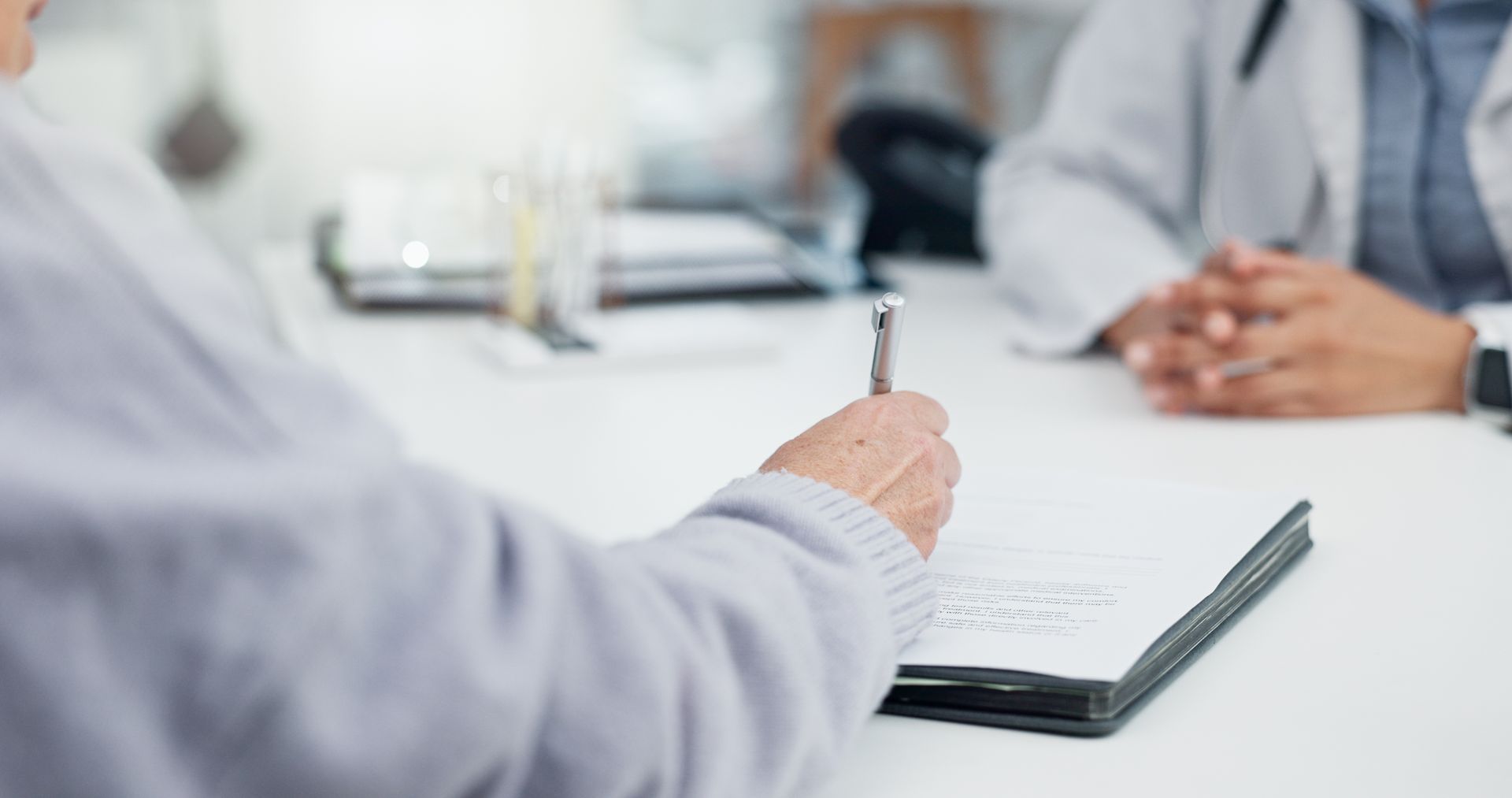 A man is sitting at a table with a pen in his hand.