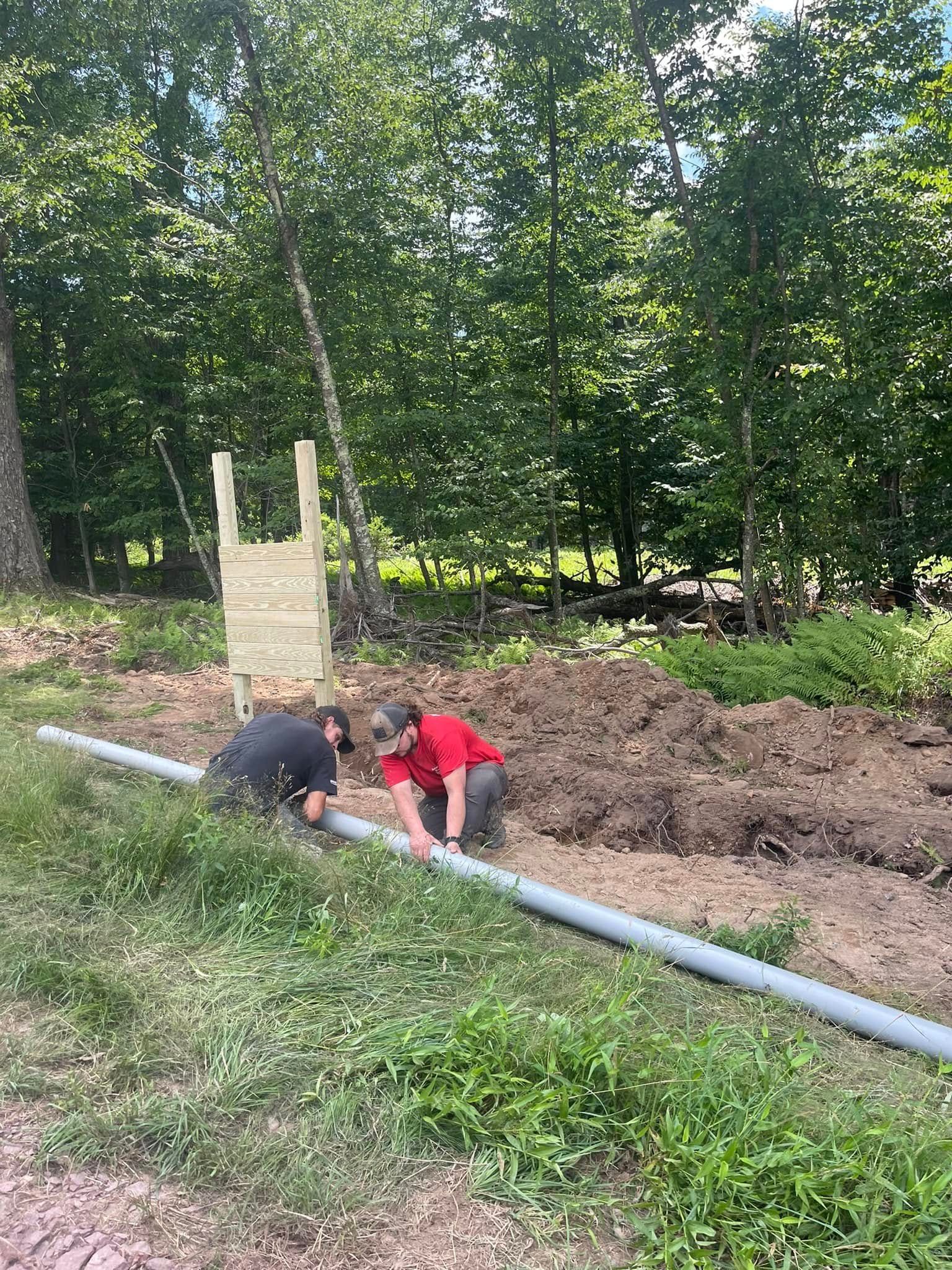 American Electric LLC | Two men are working on a pipe in the dirt.