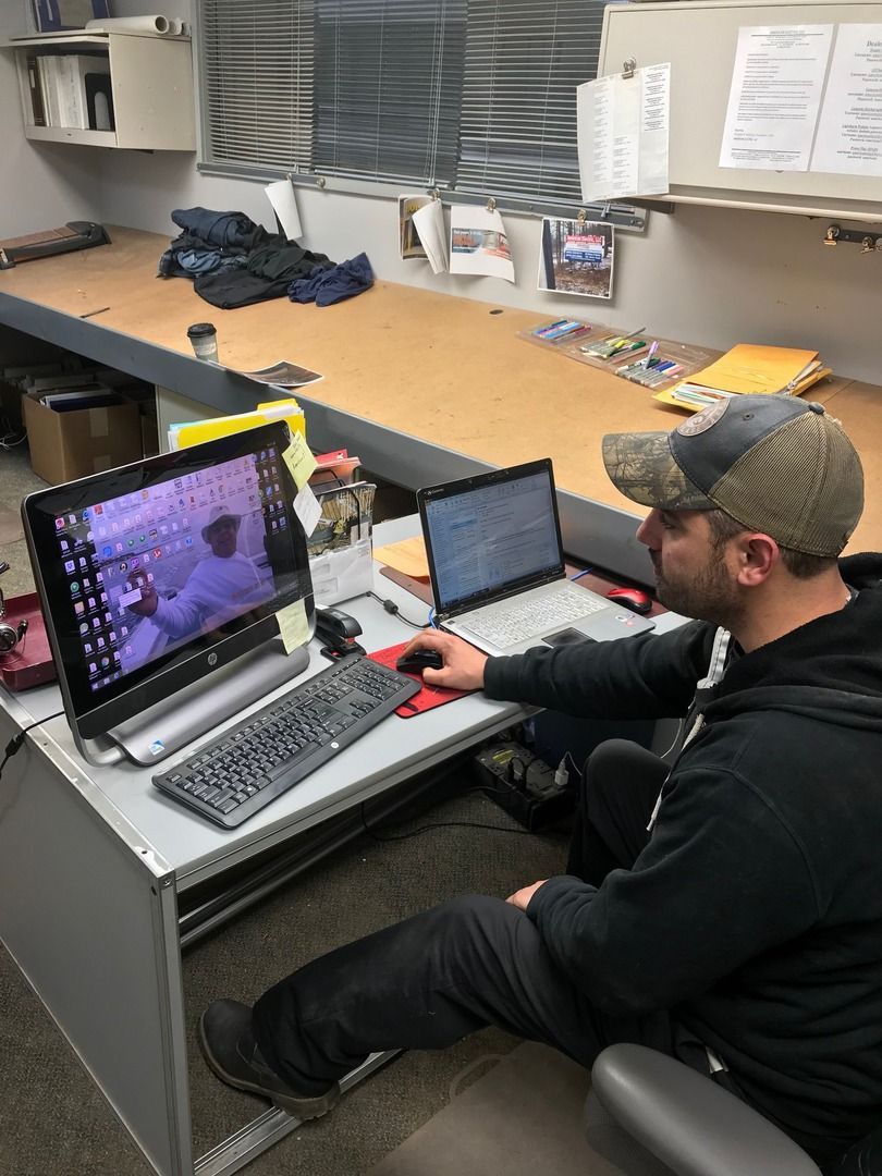 American Electric LLC | A man is sitting at a desk using a laptop computer.
