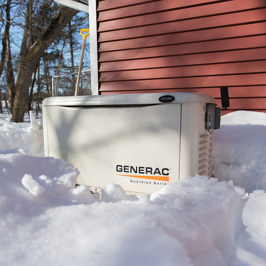 American Electric LLC | A generator is sitting in the snow in front of a red house