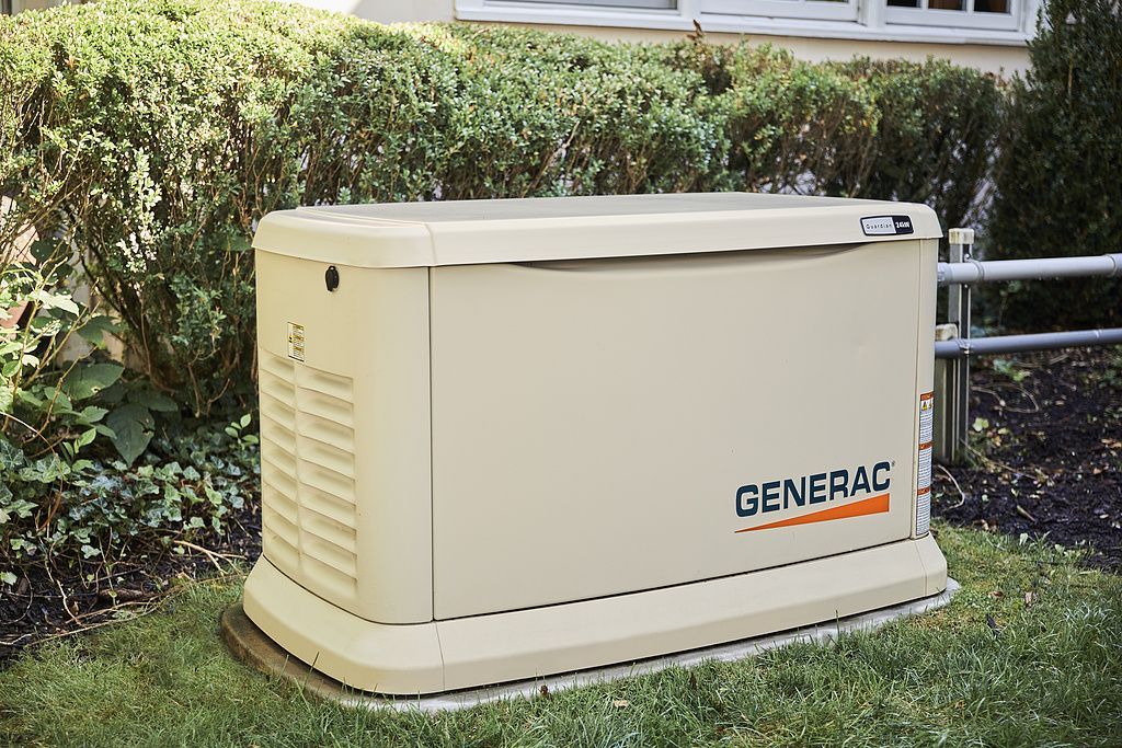 American Electric LLC | A generator is sitting in the grass in front of a house.