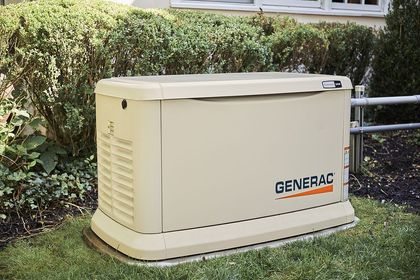 American Electric LLC | A generator is sitting in the grass in front of a house.
