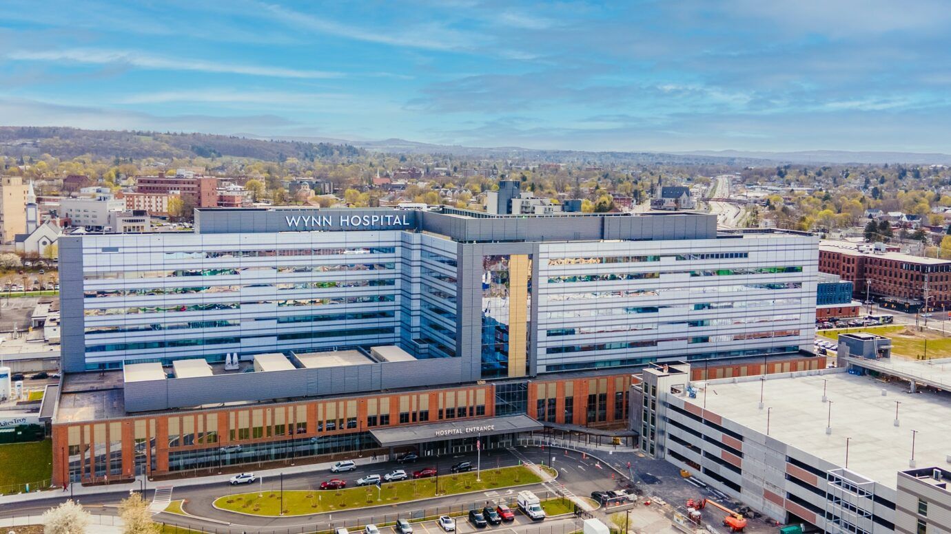 Aerial view of a modern hospital complex with glass buildings and parking lots in an urban area