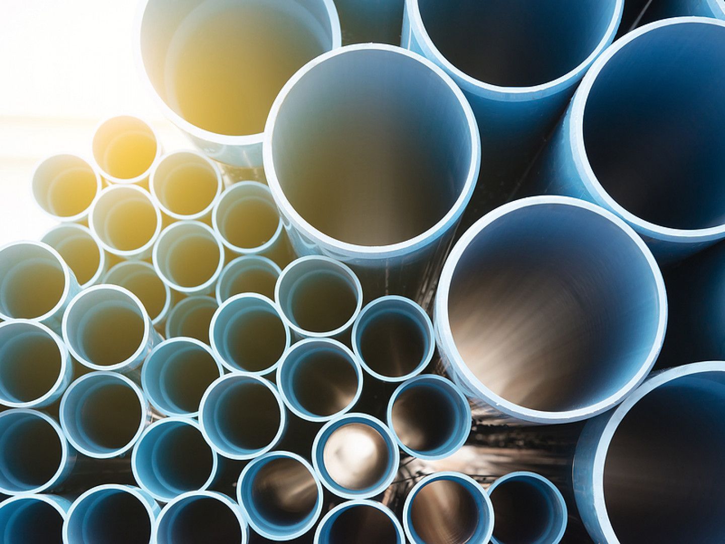 Stacked metal pipes with blue and yellow rims, viewed close up from above