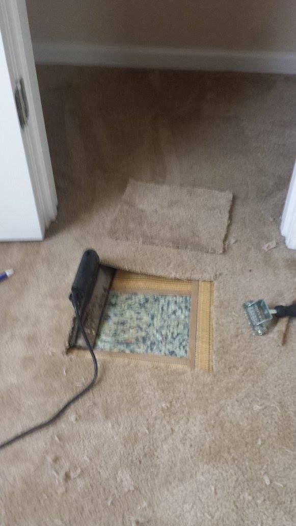 A hole in the floor of a room with a vacuum cleaner.