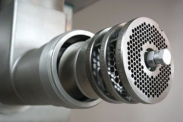 A close up of a stainless steel meat grinder.