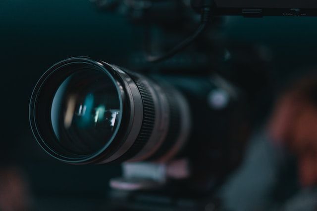 Close-up of a professional camera lens with a blurred background, representing photography and video