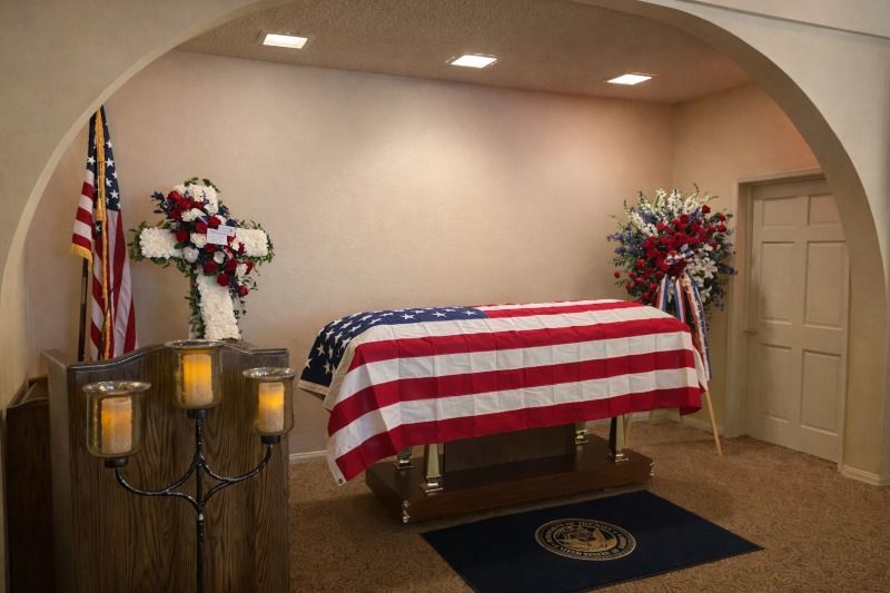 Lakewood, CA veteran services with U.S. flag-draped casket, honor guard flowers and memorial candles.