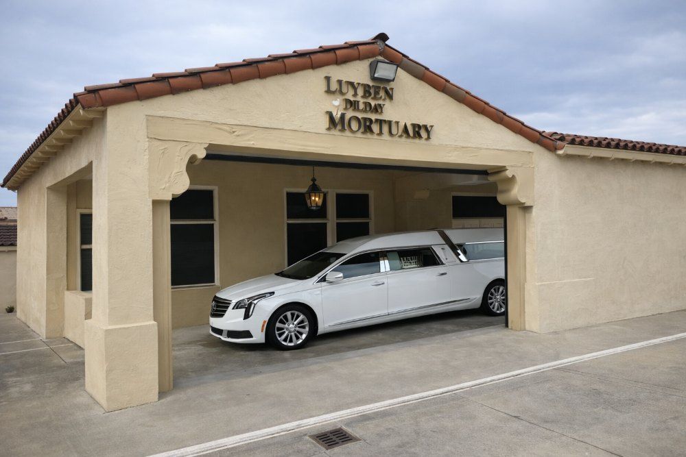 Long Beach, CA funeral home and cremations with white hearse under Luyben Dilday Mortuary portico.