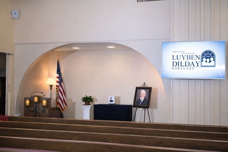 Los Alamitos, CA funeral home and cremations chapel with pews, U.S. flag, portrait and Luyben Dilday screen.