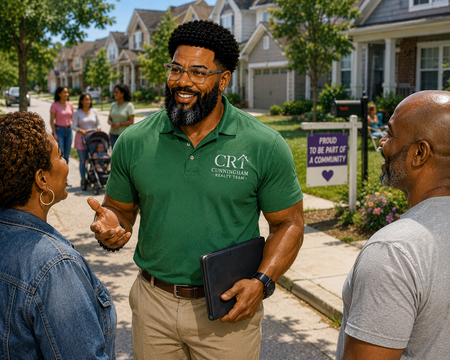 Man in green polo speaking with neighbors on a suburban sidewalk, holding a tablet and smiling.