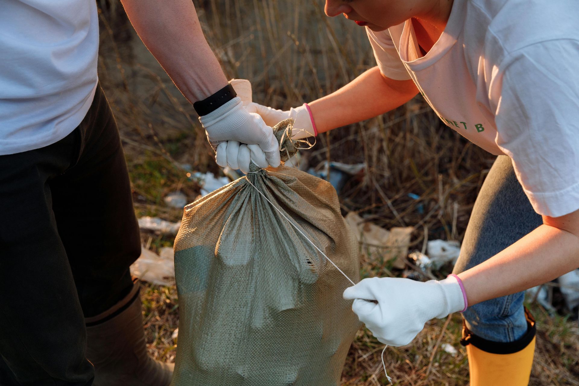 A man and a woman are holding a bag of trash.