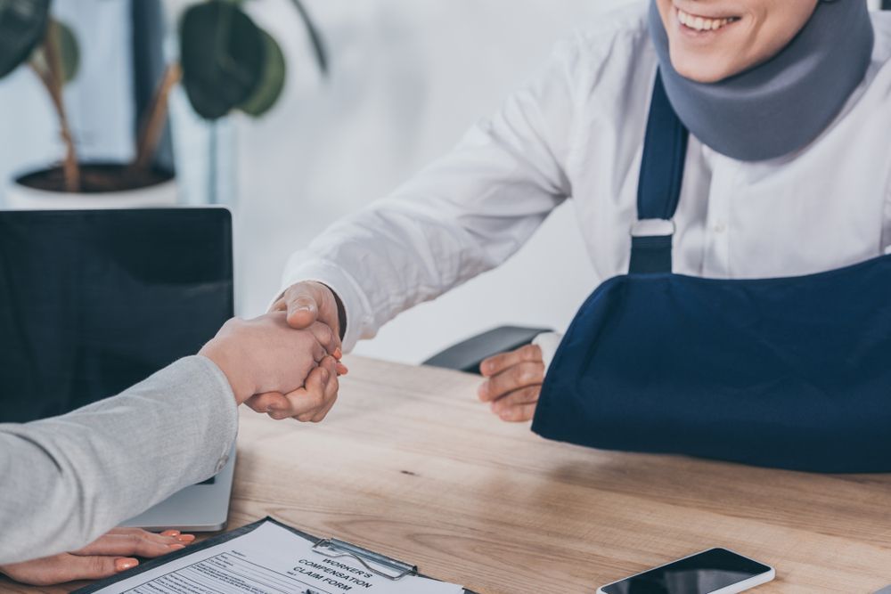 A woman with a broken arm is shaking hands with another woman.