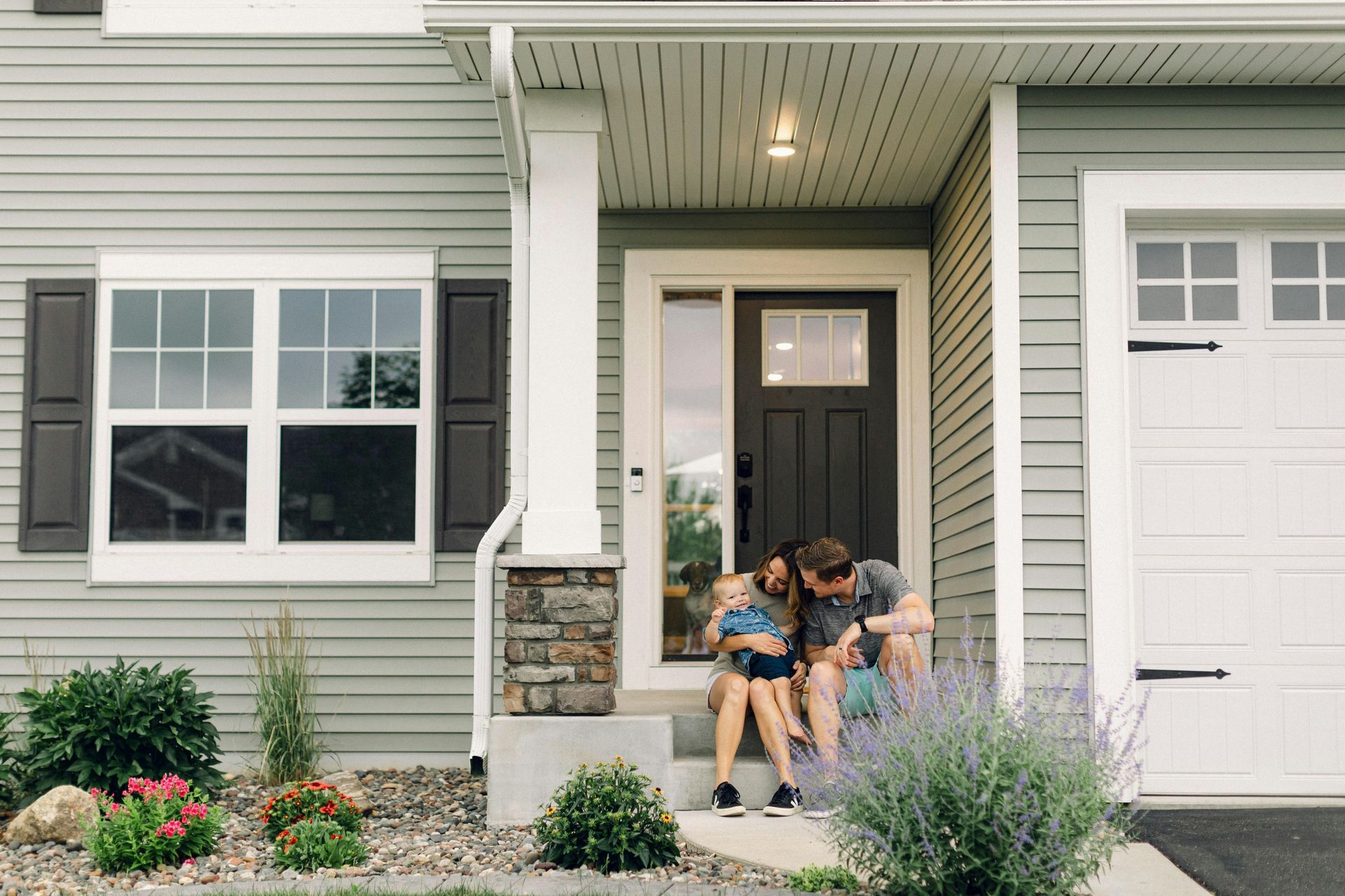Millennial couple sitting outside their first home in a suburban Michigan neighborhood