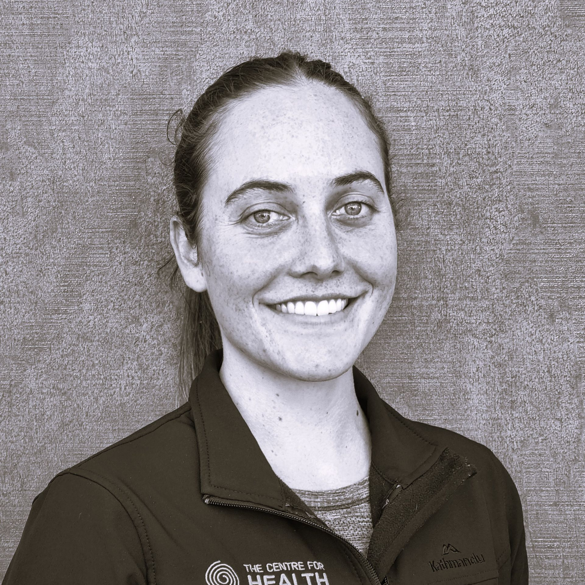 A black and white photo of a woman wearing a hoodie and smiling.