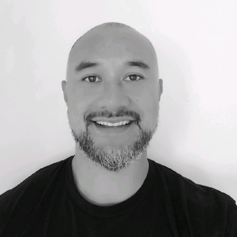 A man is smiling in a black and white photo.