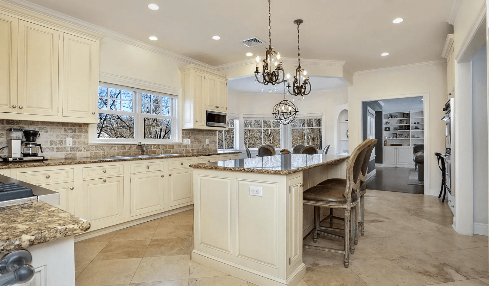 A kitchen with white cabinets , granite counter tops , and a large island.