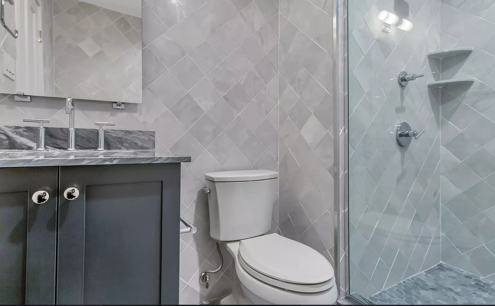 A bathroom with a toilet , sink , mirror and walk in shower.