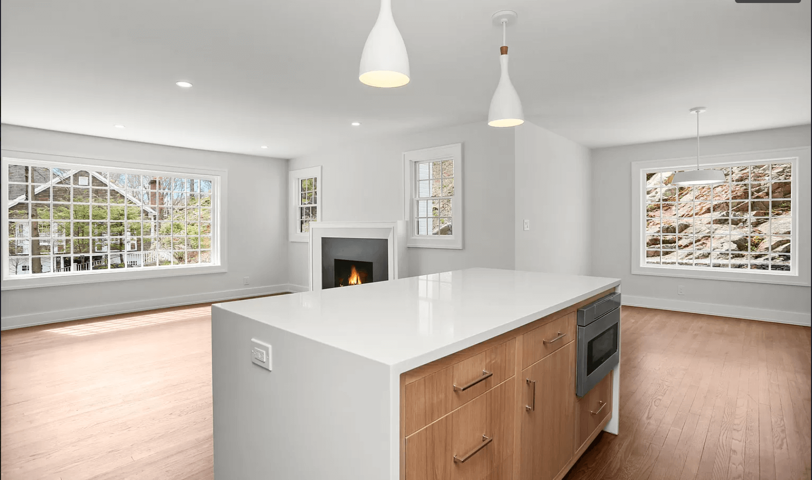 An empty kitchen with a large island and a fireplace.