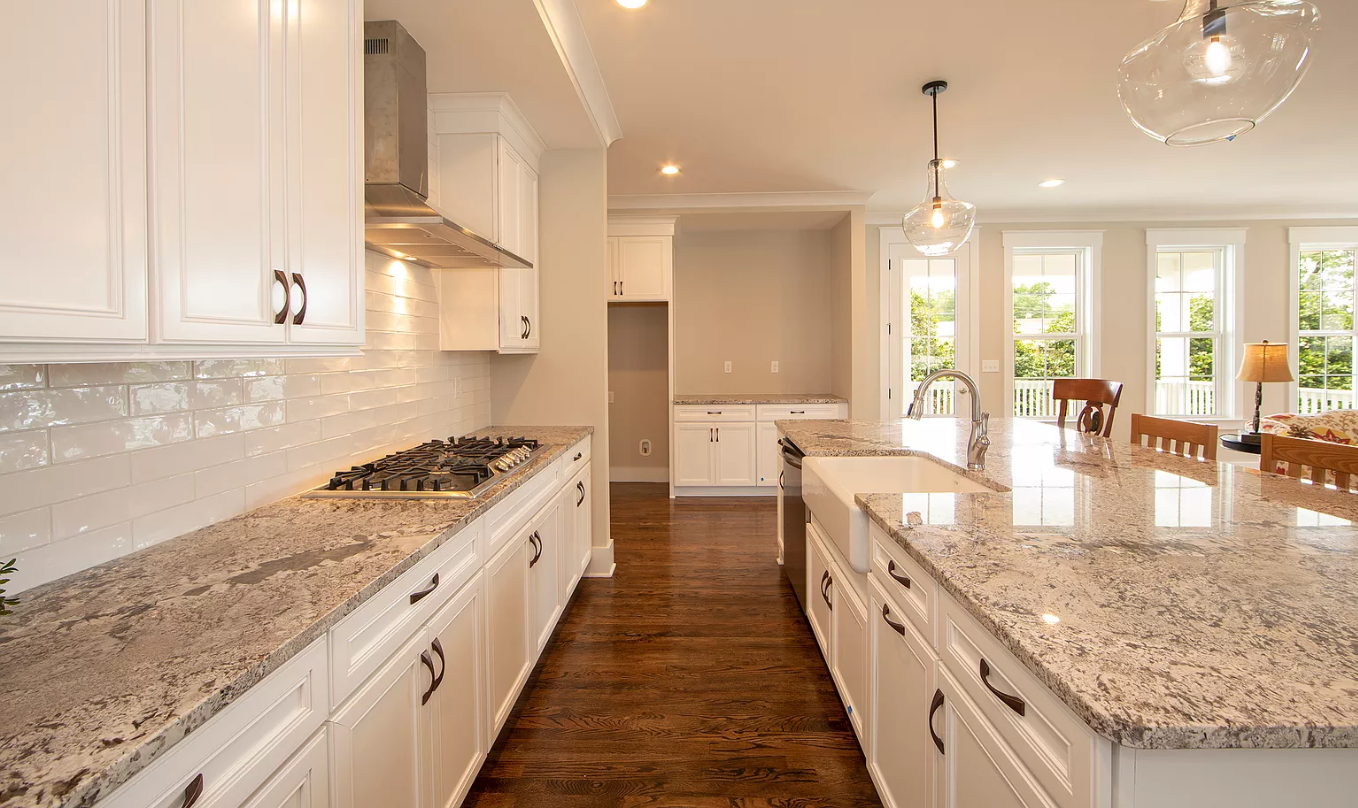 A kitchen with granite counter tops and white cabinets.