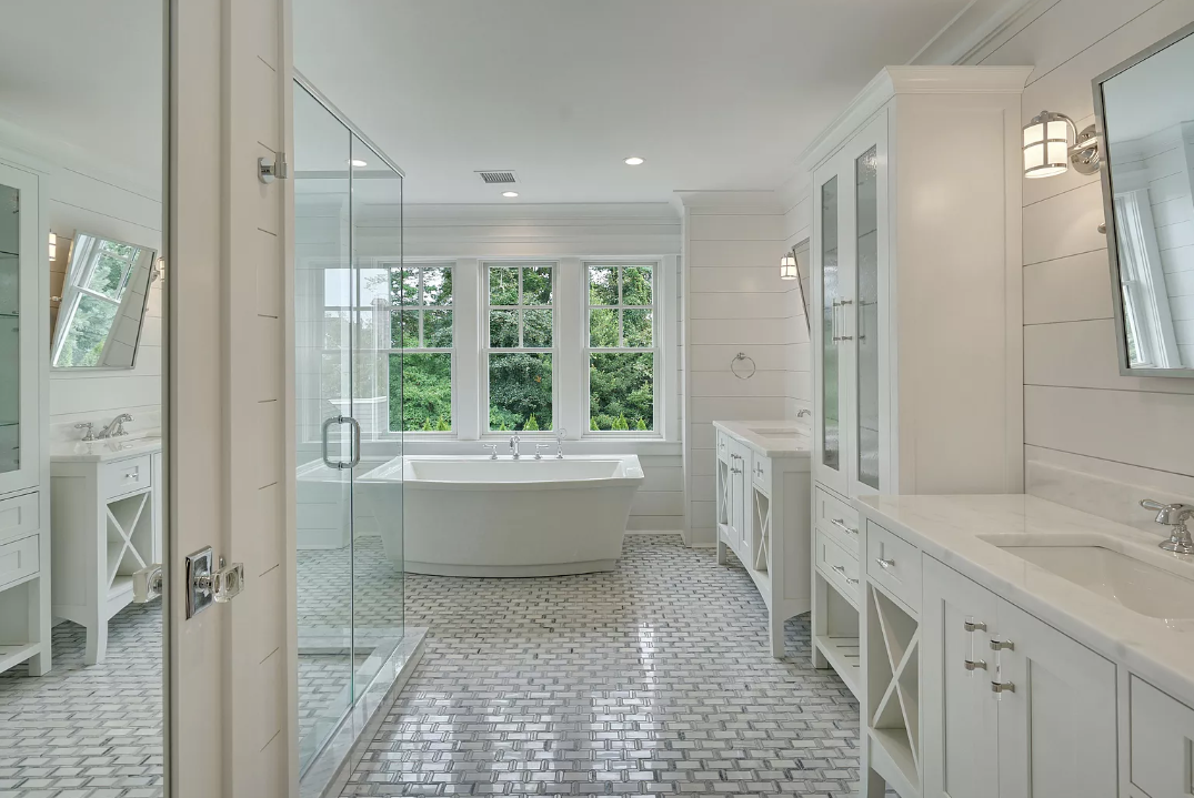 A bathroom with a tub , sinks , mirrors and a walk in shower.