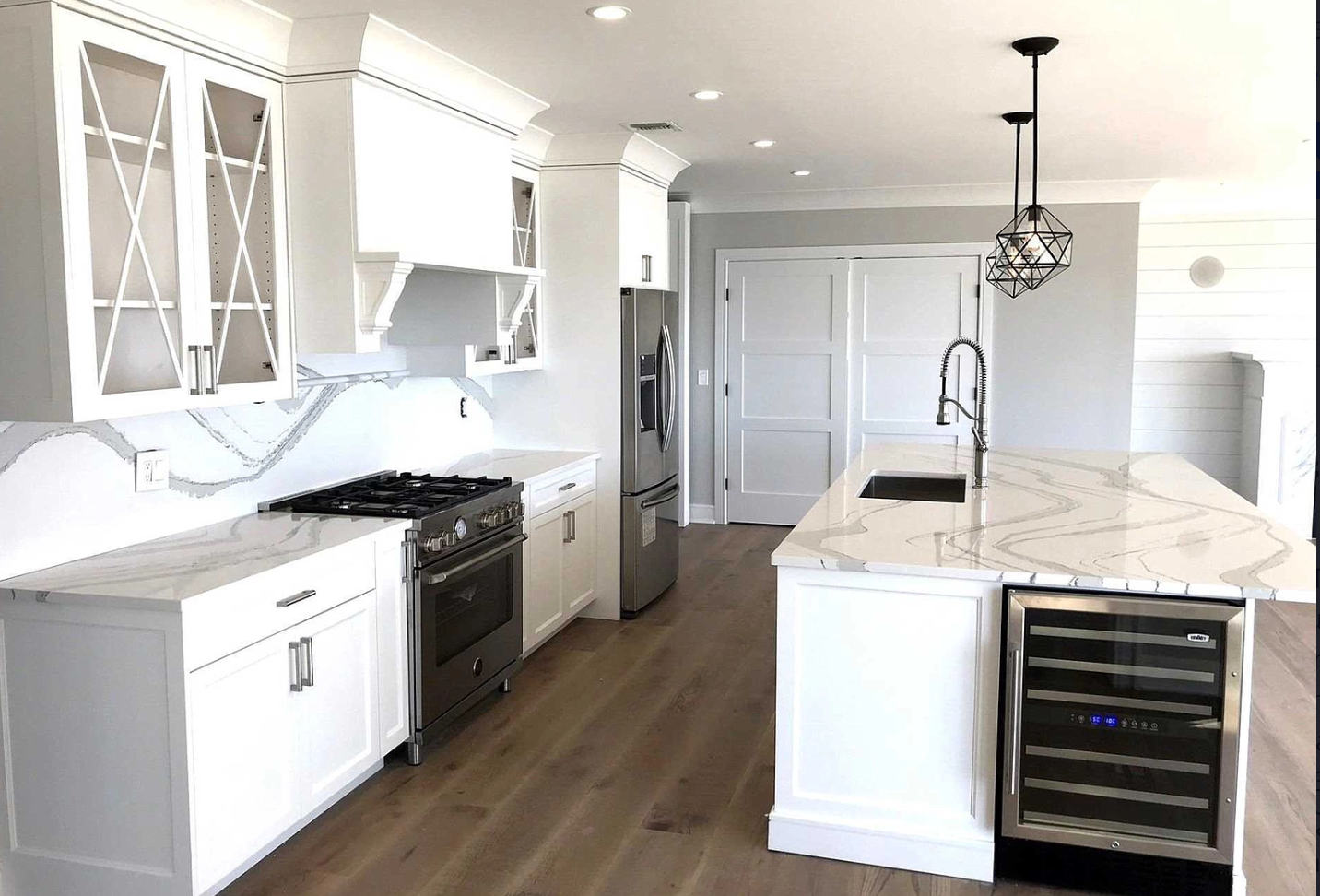 A kitchen with white cabinets , stainless steel appliances , and a large island.