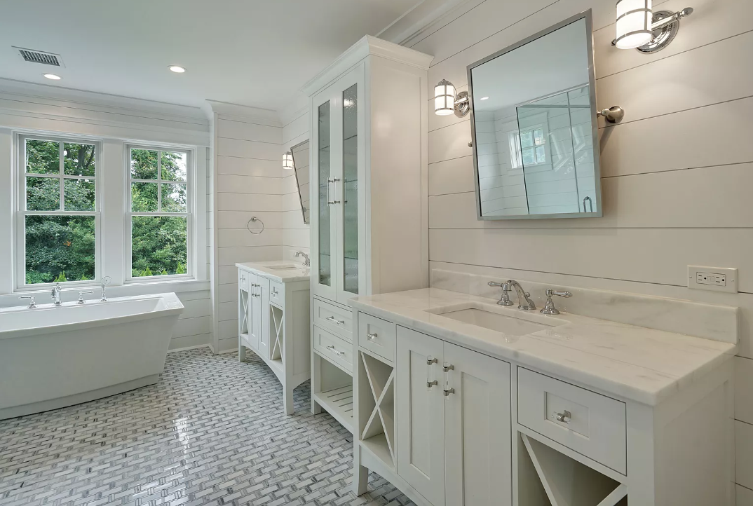 A bathroom with two sinks , a tub and a mirror.