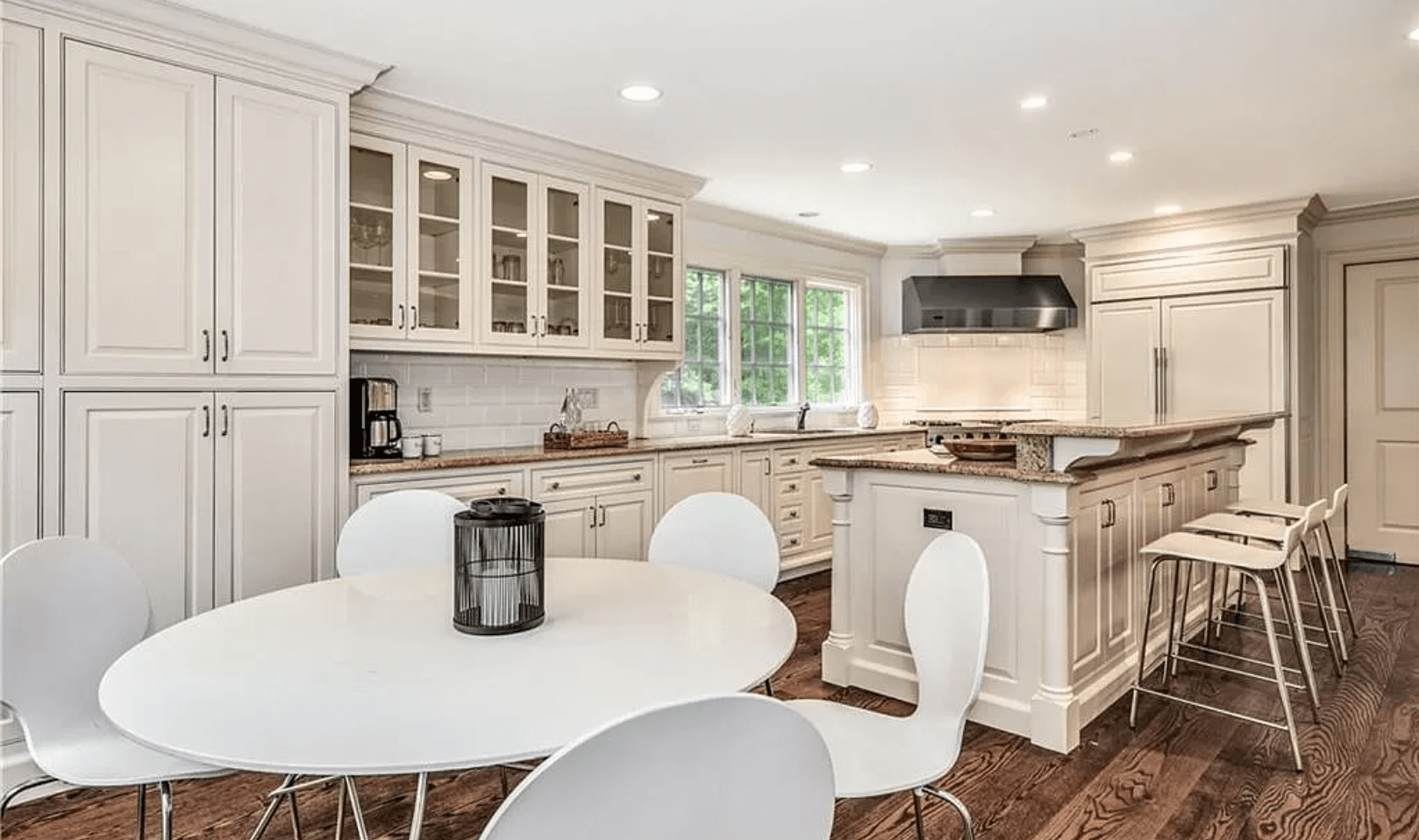 A kitchen with white cabinets , a round table and chairs.