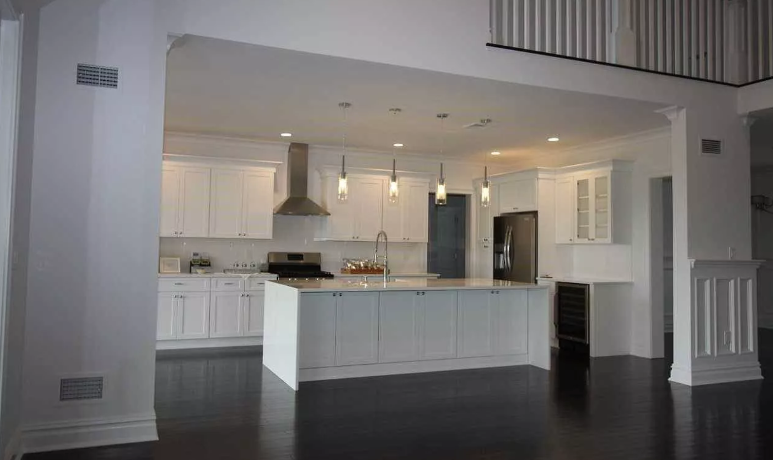 An empty kitchen with white cabinets and a large island.