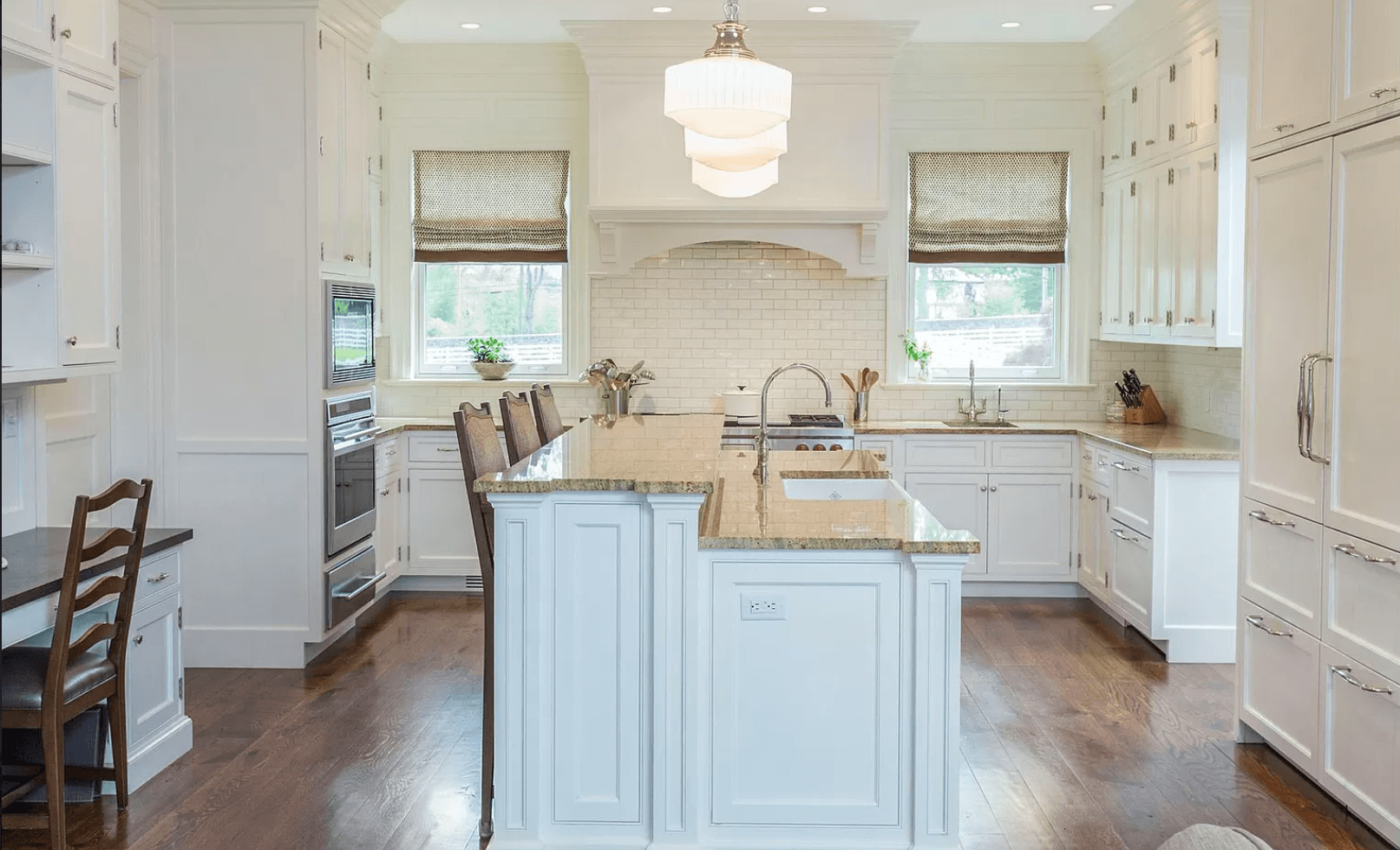 A kitchen with white cabinets , granite counter tops , and a large island.