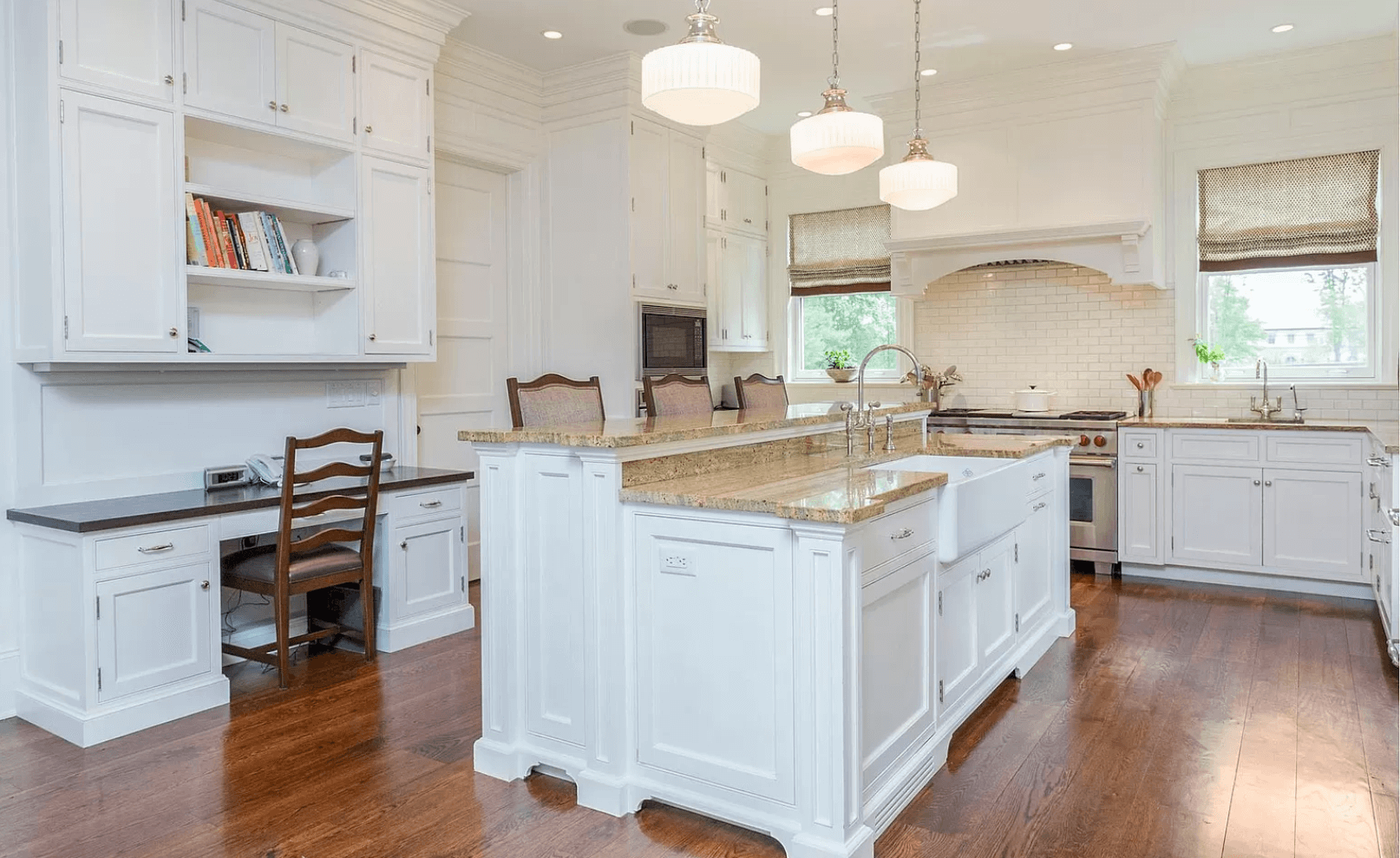 A kitchen with white cabinets , granite counter tops , and a large island.