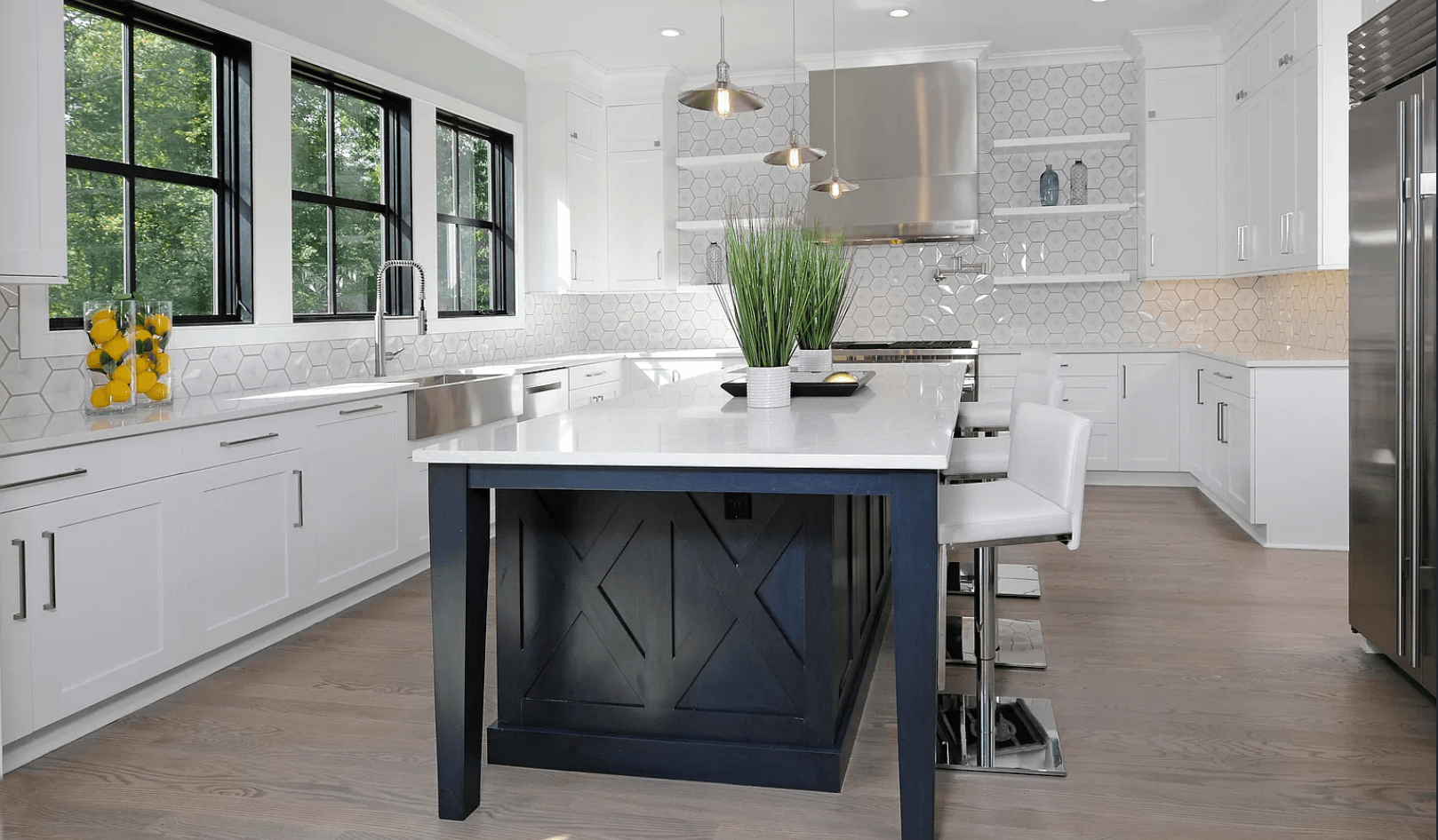A kitchen with white cabinets , stainless steel appliances , and a large island.